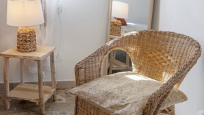 A wicker chair with a floral cushion, a small wooden table with a woven lamp, and a mirror reflecting the lamp and chair. - Room 3 – Spacious Double Room with Shared Pool, Wi-Fi, and Air Conditioning (Cavaion Veronese)