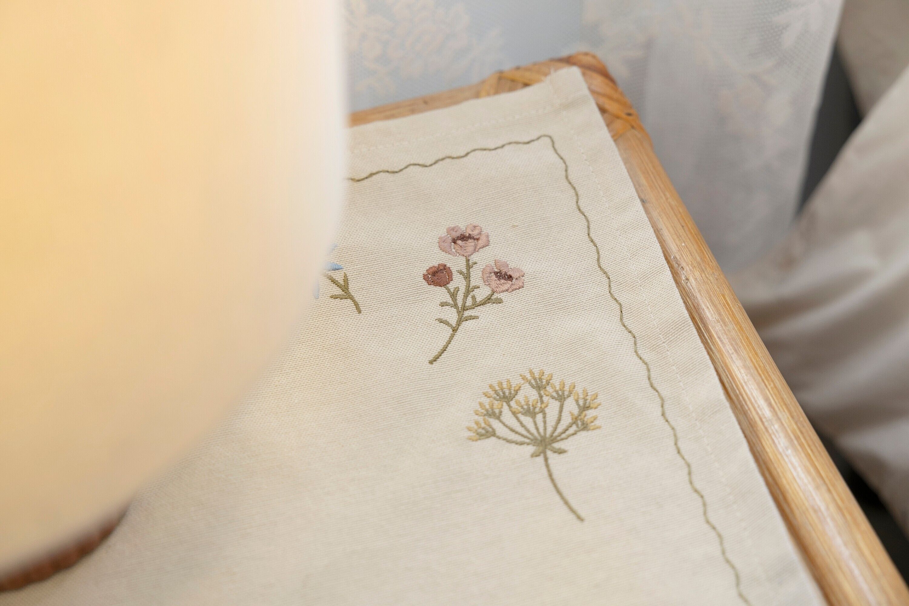Detalhe de um tecido com flores bordadas e moldura de madeira.