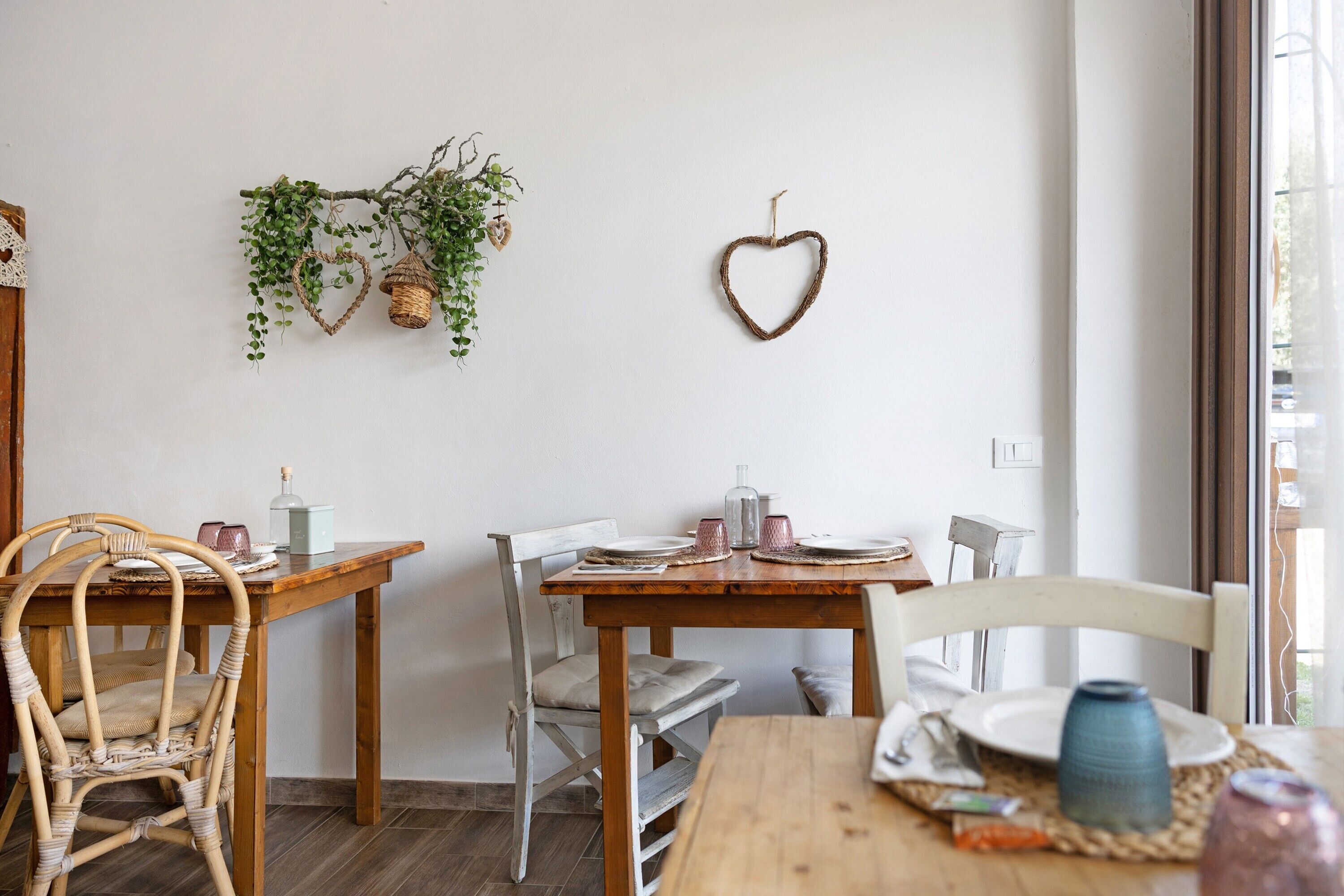 Un coin repas avec une table en bois, des chaises et une décoration en forme de cœur accrochée au mur.