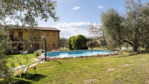 Uma área de piscina com um edifício, móveis de exterior e árvores.