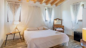 A bedroom with a bed, bedside table, lamp, and a small wooden cabinet. - Room 6 – Spacious Double with Shared Pool, Wi-Fi, and Air Conditioning (Cavaion Veronese)