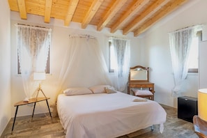 A bedroom with a bed, bedside table, lamp, and a small wooden cabinet. - Room 6 – Spacious Double with Shared Pool, Wi-Fi, and Air Conditioning (Cavaion Veronese)