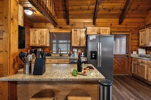 A kitchen with wooden cabinets, granite countertops, a stainless steel refrigerator, and a built-in oven. - 2 King Suites - Hot Tub - Fire Pit (Pigeon Forge)