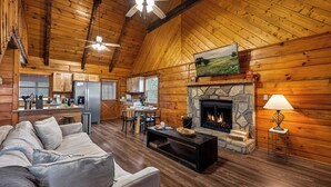 Un salón espacioso con chimenea, techo de madera y una zona de estar acogedora.