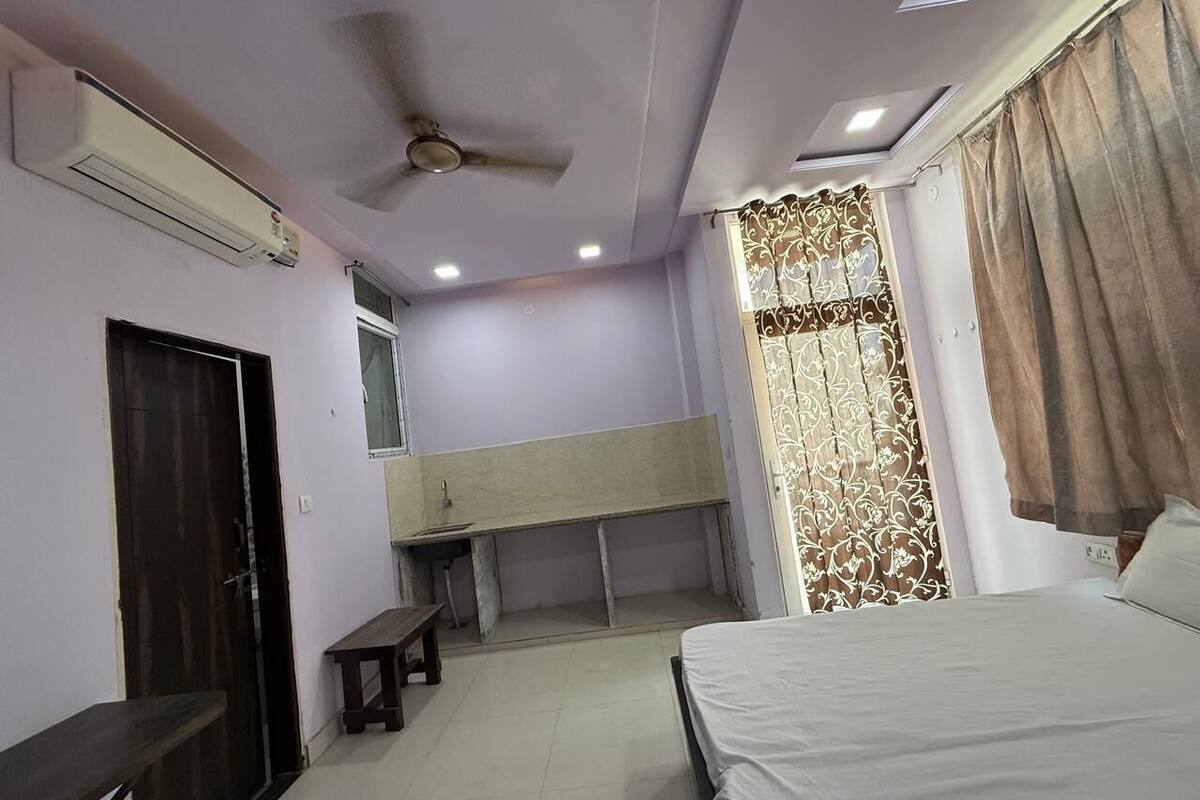 Ein Schlafzimmer mit einem Bett, einem Schreibtisch, einer Bank, einem Deckenventilator und einem Fenster mit Vorhängen.