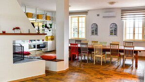 A spacious kitchen with a dining area, wooden flooring, and large windows providing natural light. - Mary Jungle (Sant'Elpidio a Mare)