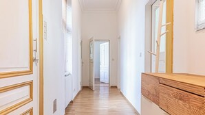 A hallway with wooden flooring, white walls, and a wooden cabinet. - Cozy Room Near Landstraße for Long Stay (Vienna)