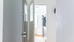A narrow hallway leading to a kitchen with white cabinets and a window. - Cozy Room Near Landstraße for Long Stay (Vienna)