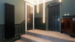A staircase with carpeted steps leading to a dark wooden door. - The Hyde (Preston)