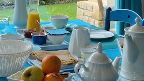 Una mesa de desayuno con diversos alimentos, una jarra, tazones y un jarrón con tulipanes amarillos.