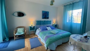 Un dormitorio con cama, una silla, un escritorio, un espejo y una ventana con cortinas.
