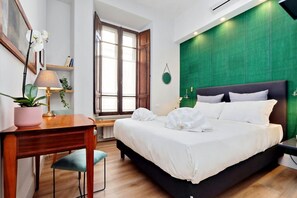 Ein Schlafzimmer mit einem großen Bett, einem Schreibtisch mit Lampe und einem Fenster mit Holzjalousien.