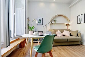 Een moderne woonkamer met een ronde tafel, een groene stoel, een beige bank en een houten bankje.