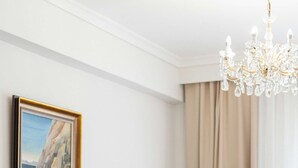 Ein Wohnzimmer mit einem beigen Sofa, einem passenden Sessel, einem runden Couchtisch, einer Kristallleuchtre und einem gerahmten Gemälde an der Wand.