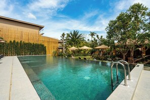 Una piscina al aire libre, sombrillas, sillones reclinables de piscina