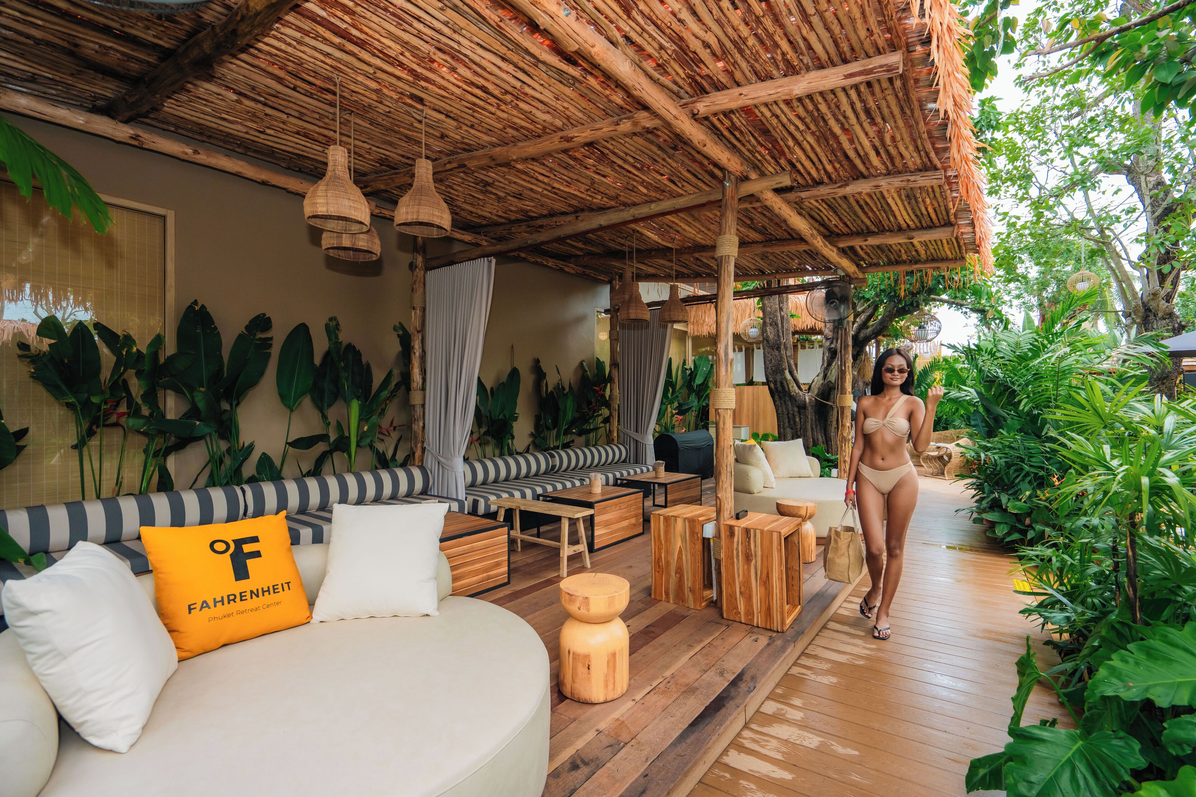 Habitación de estilo tropical con techo de paja, muebles de madera y abundante follaje.