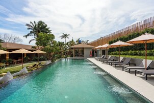 Una piscina al aire libre, sombrillas, sillones reclinables de piscina