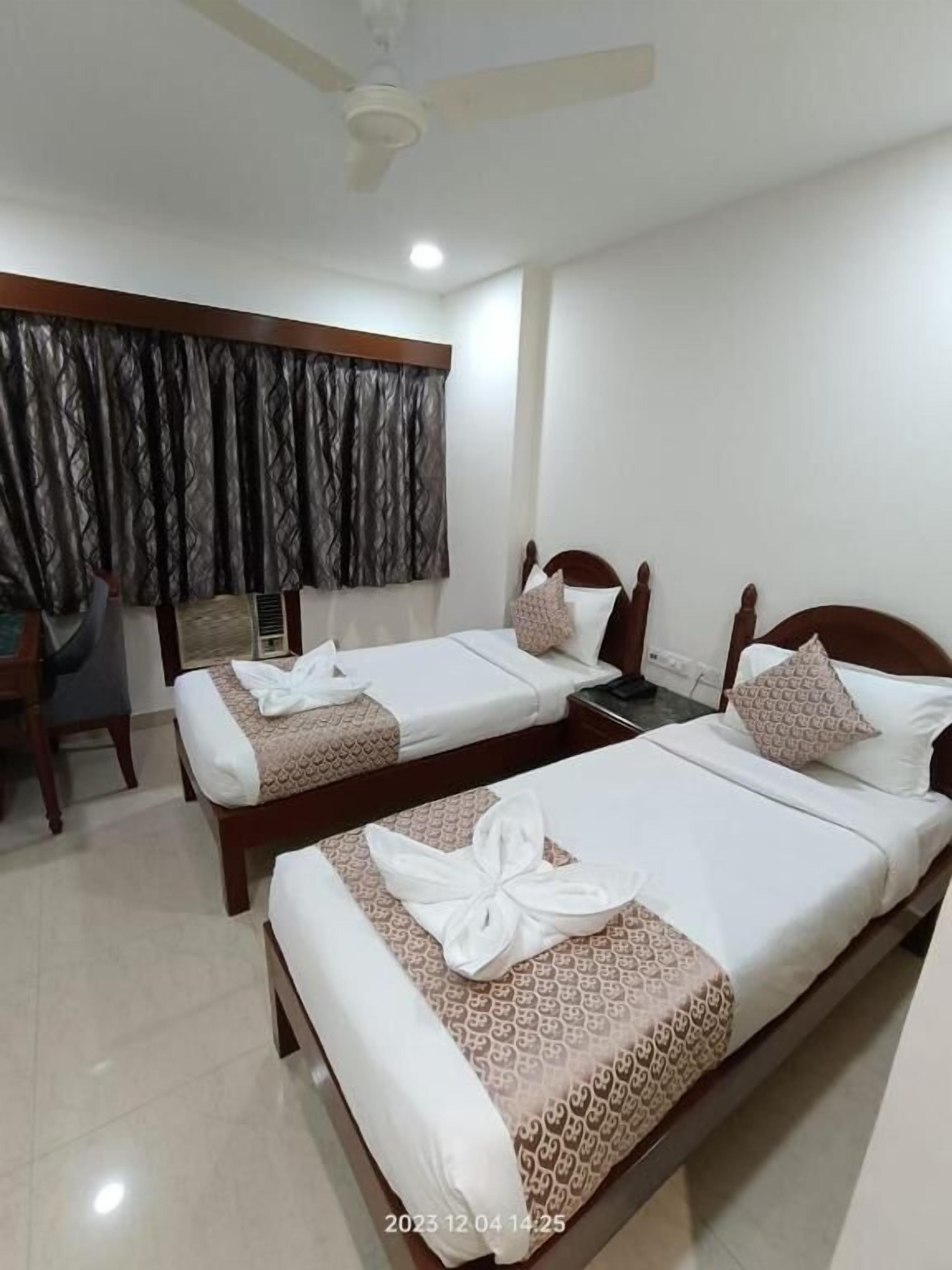 A hotel room with two single beds, a desk, and a chair.