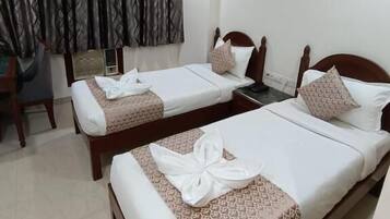 A hotel room with two single beds, a desk, and a chair.