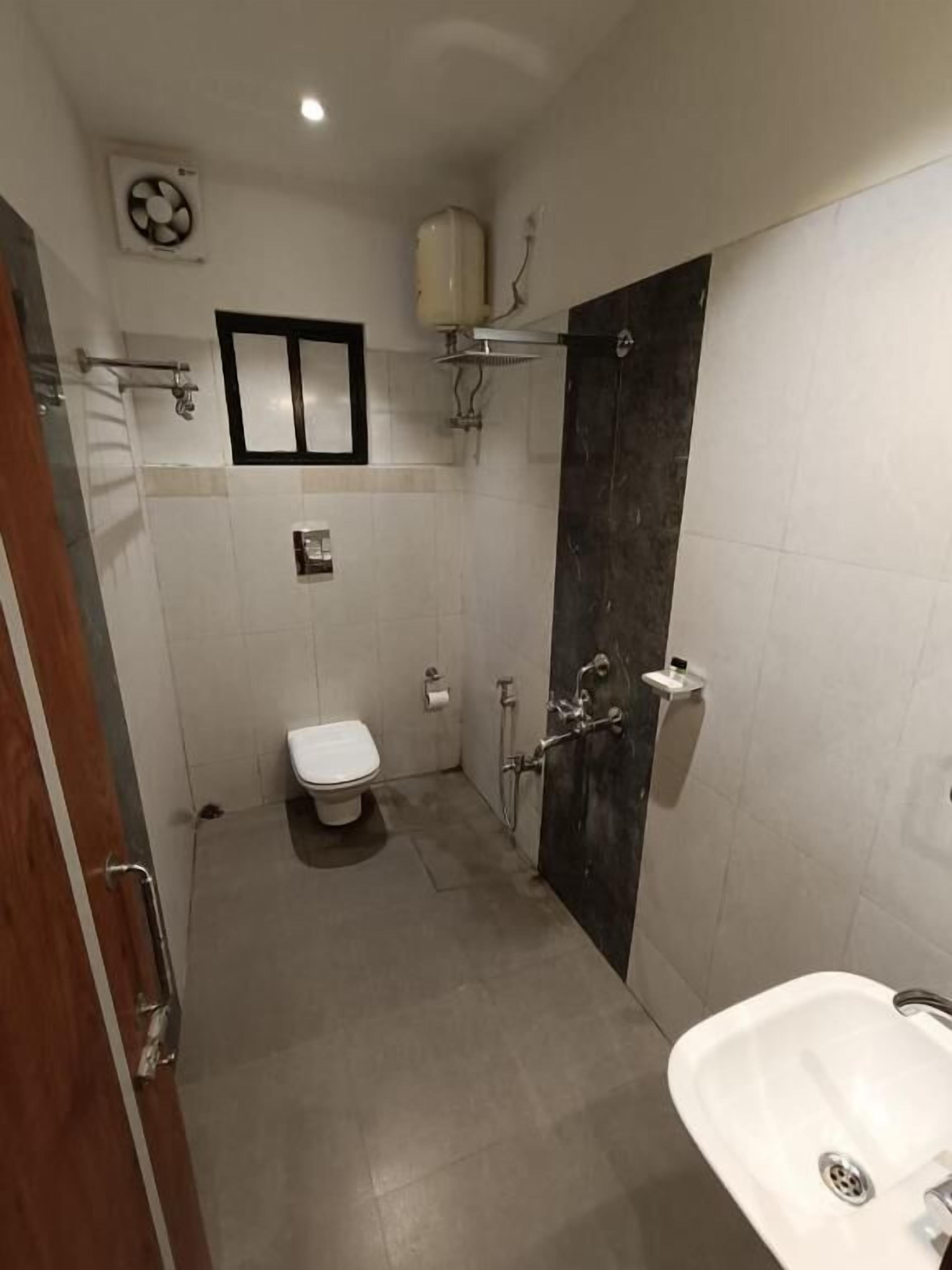 A bathroom with a toilet, a sink, and a shower area.
