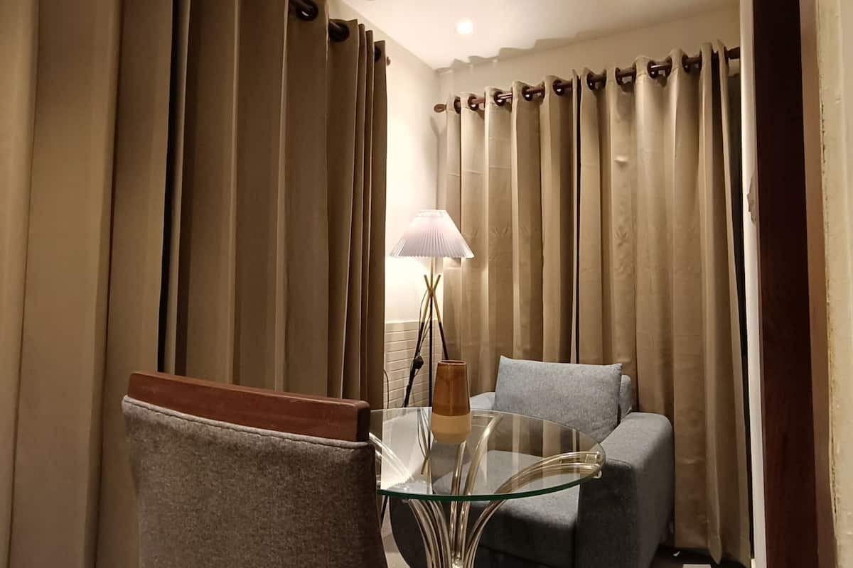 Una sala de estar moderna con una mesa de centro de vidrio, un sofá gris y un comedor con una silla.