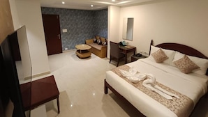 Une chambre d’hôtel équipée d’un lit, d’un bureau, d’une chaise, d’une télévision, d’un ventilateur de plafond et d’une salle de bain.