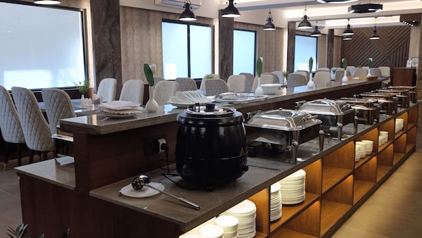 Un buffet moderne, avec un îlot central, plusieurs espaces pour s’asseoir et des luminaires suspendus.
