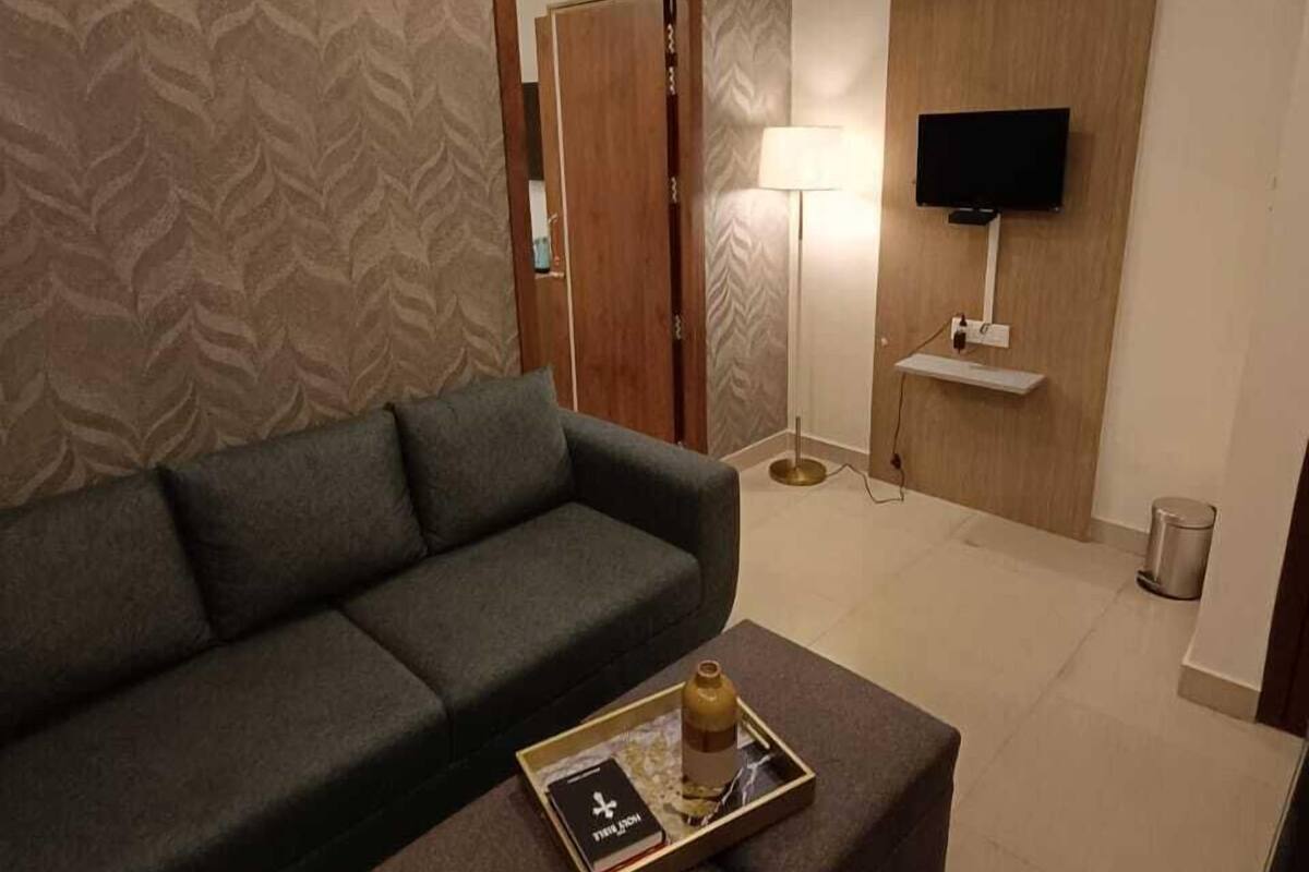 Una sala de estar moderna con un sofá verde, una mesa de centro con bandeja, una lámpara y un televisor montado en la pared.
