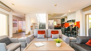 A modern living room with a sofa, coffee table, and a view into the kitchen.