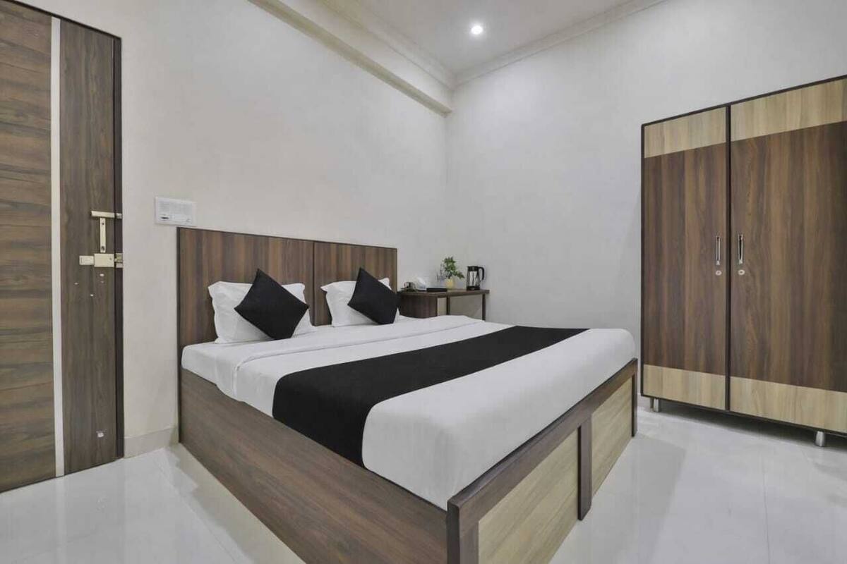 A modern bedroom with a wooden bed frame, a large wardrobe, and a bedside table with a lamp.