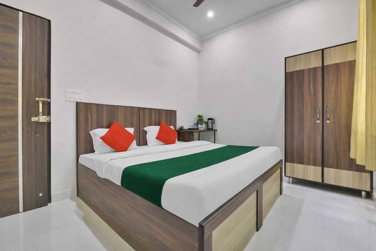 A modern bedroom with a wooden bed, white bedding, and a green throw.