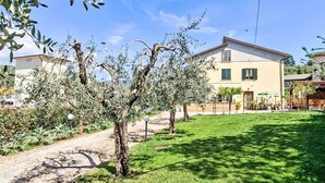 A residential property with a well-maintained lawn, a pathway, and a building with a beige facade and green shutters. - tre fontane by Interhome (Monsummano Terme)
