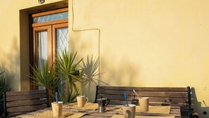 An outdoor dining area with wooden benches and tables, equipped with cutlery and cups, surrounded by potted plants. - tre fontane by Interhome (Monsummano Terme)
