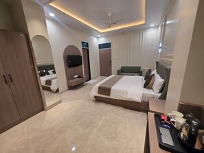 Una habitación de hotel moderna con una cama grande, un televisor de pantalla plana, un sofá y una cafetera.