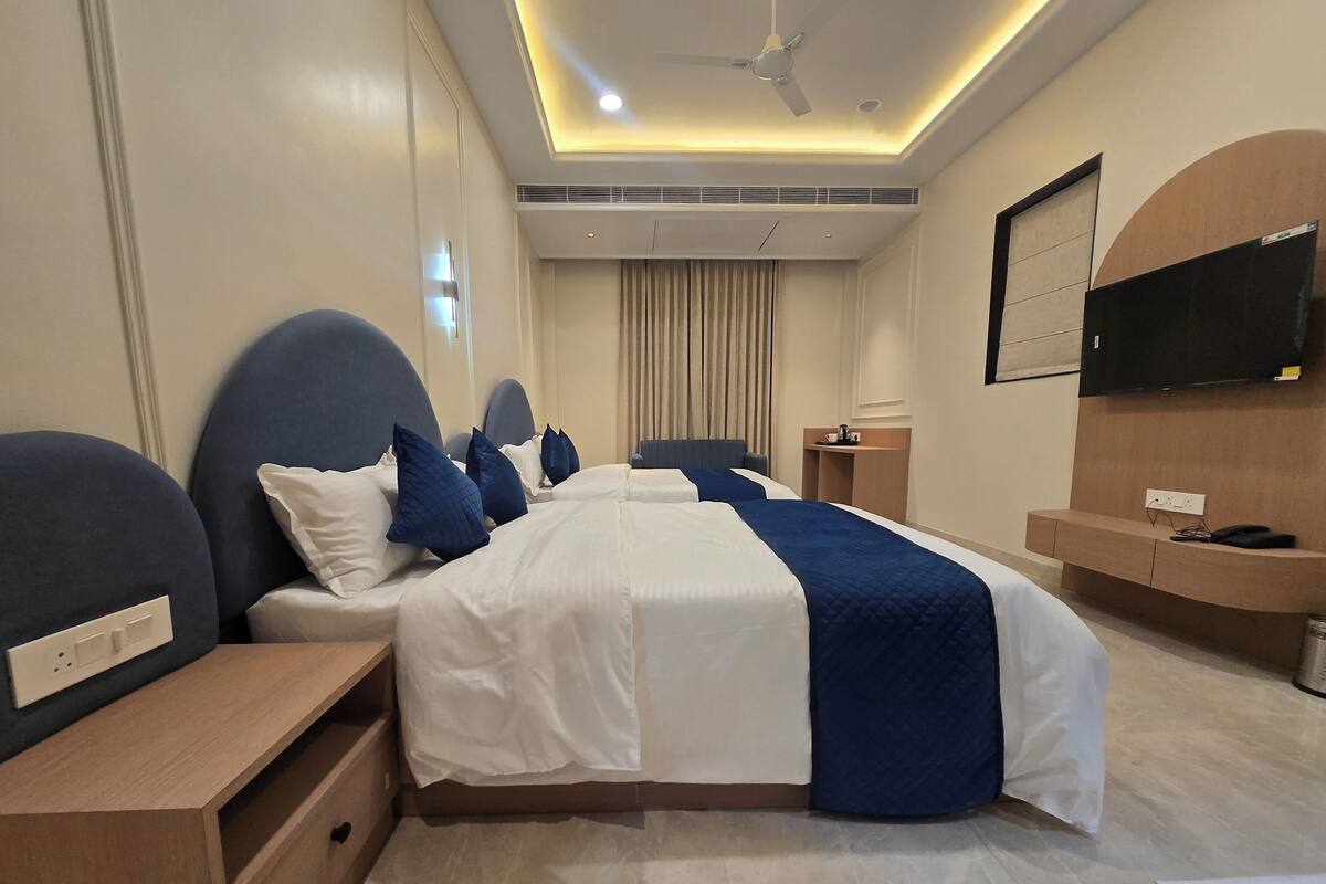 Een hotelkamer met een groot bed, nachtkastjes, een bureau, een flatscreen televisie en een plafondventilator.