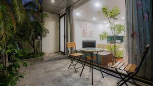 A modern living room with a glass door leading to a balcony, furnished with a sofa, chairs, and a coffee table. - Sakamoto 1 Apartments by XÔI Residences (Hanoi)