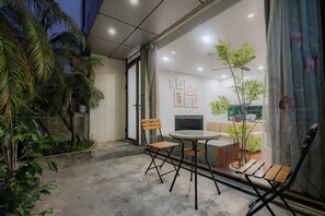 A modern living room with a glass door leading to a balcony, a round glass table, and two wooden chairs. - Sakamoto 1 Apartments by XÔI Residences (Giang Vo)
