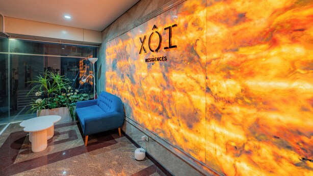 A modern lobby with a blue sofa, a small round table, and a glass wall with a fiery design. - Sakamoto 1 Apartments by XÔI Residences (Hanoi)