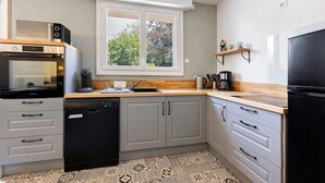 A modern kitchen with a dishwasher, microwave, and refrigerator. - La maison du sabotier – Spacious Family Home for 14 Guests (Saint-Malô-du-Bois)