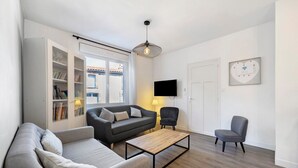 A modern living room with a sofa, armchair, coffee table, and a TV. - La maison du sabotier – Spacious Family Home for 14 Guests (Saint-Malô-du-Bois)