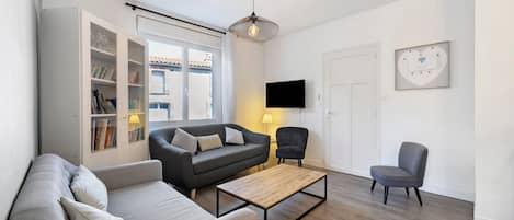 A modern living room with a sofa, armchair, coffee table, and a TV.