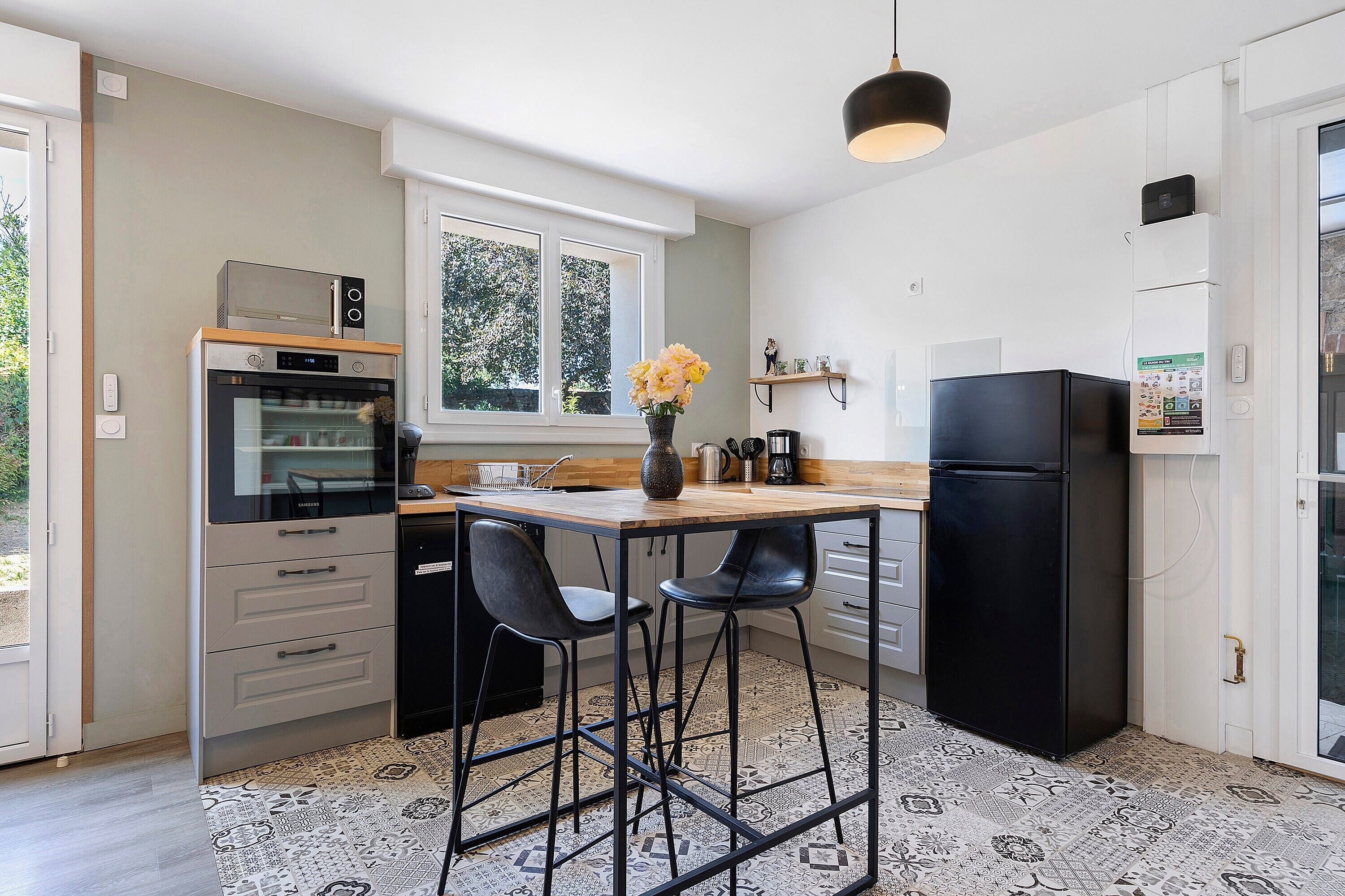 Eine moderne Küche mit Backofen, Kühlschrank und einem Fenster mit Blick auf Grünflächen.