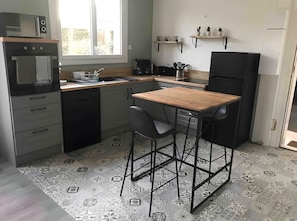 Une cuisine compacte équipée d’un four à micro-ondes, d’un évier et d’un petit coin repas avec des tabourets.