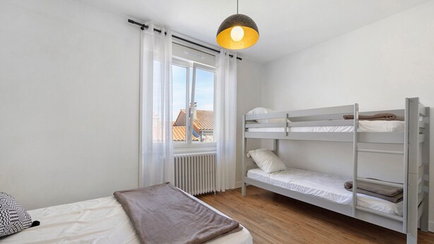 A bunk bed room with a window, a radiator, and a hanging light fixture. - La maison du sabotier – Spacious Family Home for 14 Guests (Saint-Malô-du-Bois)