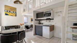 A modern kitchen with a dining area, a loft bedroom, and a view of the sea.