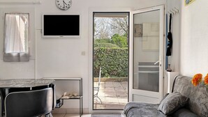 A room with a dining table, chairs, a sofa, a TV, and a sliding glass door to the outside.