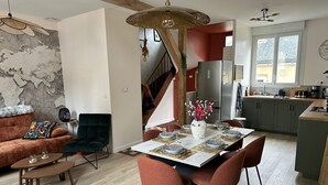Cozinha moderna com área de refeições, piso de madeira e escada para um andar superior.