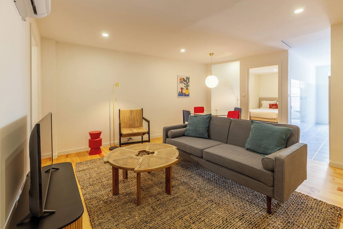 A modern living room with a sofa, a coffee table, a TV, and a chair.