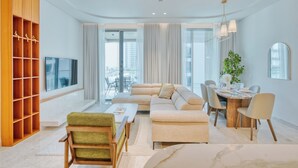 Una sala de estar moderna con un sofá, sillas, una mesa de comedor y un televisor.