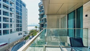 Un edificio moderno con un balcón de vidrio que ofrece vistas a un paisaje urbano y al agua.